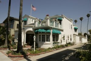 Chic white house in Long Beach with green awnings and balcony, a showcase of general contracting excellence